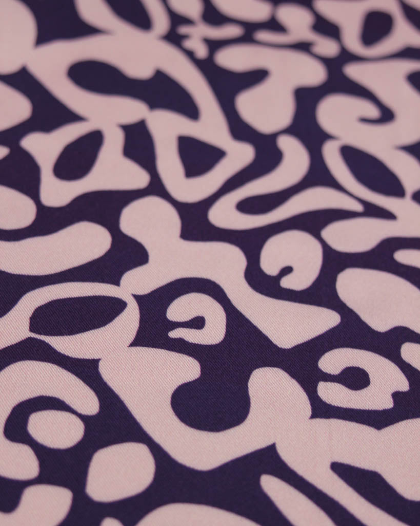 Patterned viscose twill fabric with abstract shapes on a purple background