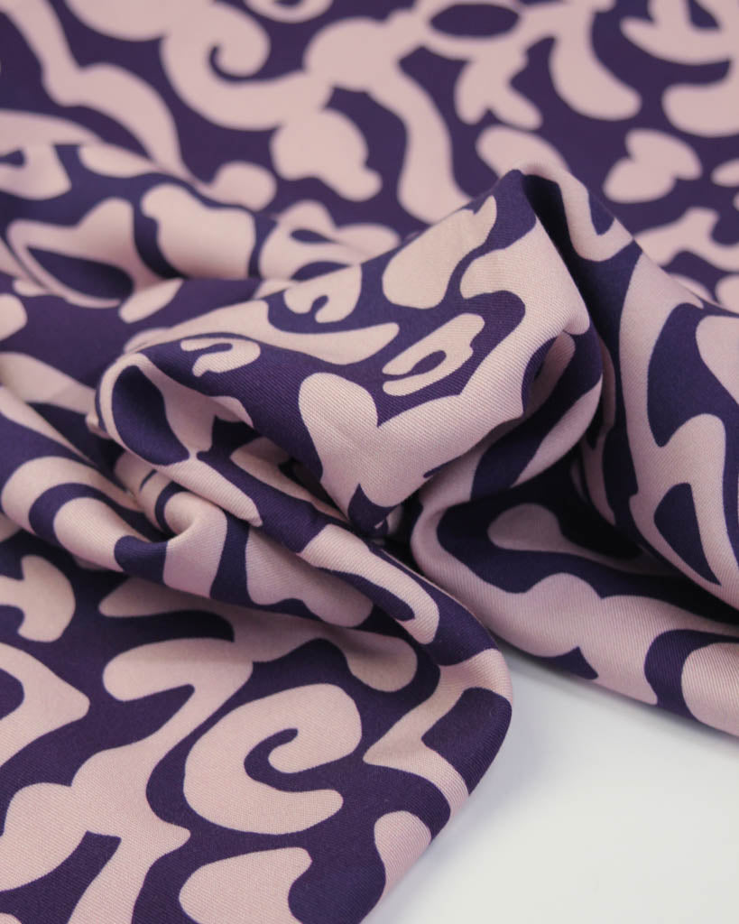 Purple abstract patterned viscose twill fabric on a white background