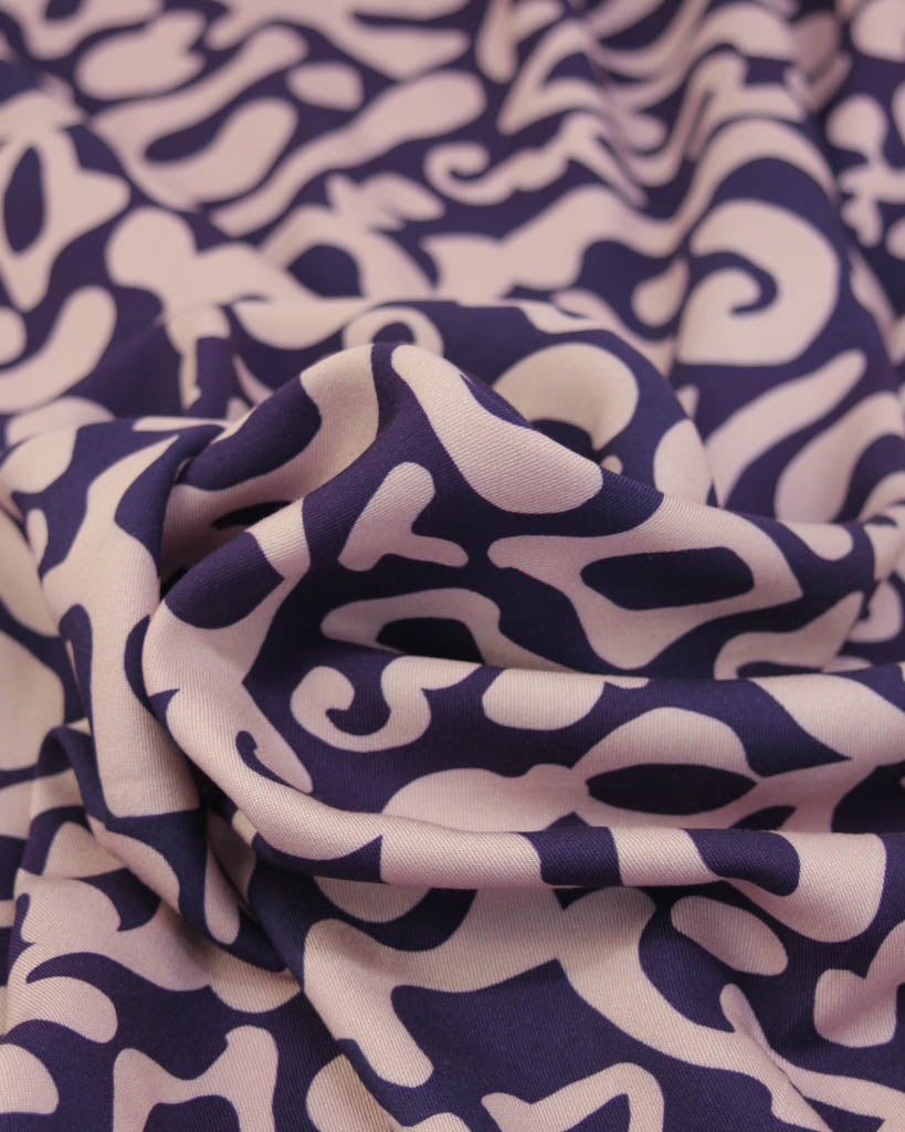 Close up of a abstract patterned purple viscose twill fabric