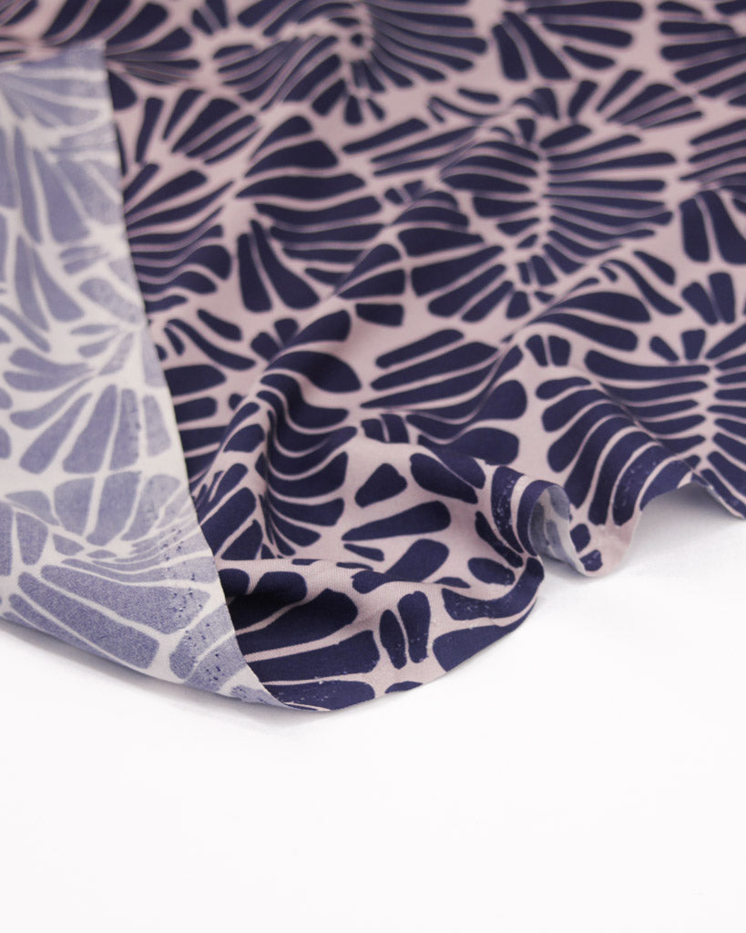 Viscose twill fabric featuring an all-over palm fan motif in deep, rich purple on a soft dusty mauve ground