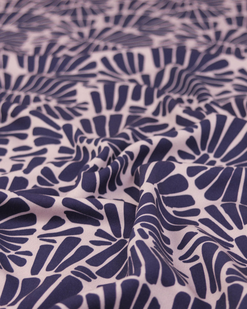 Viscose twill fabric featuring an all-over palm fan motif in deep, rich purple on a soft dusty mauve ground