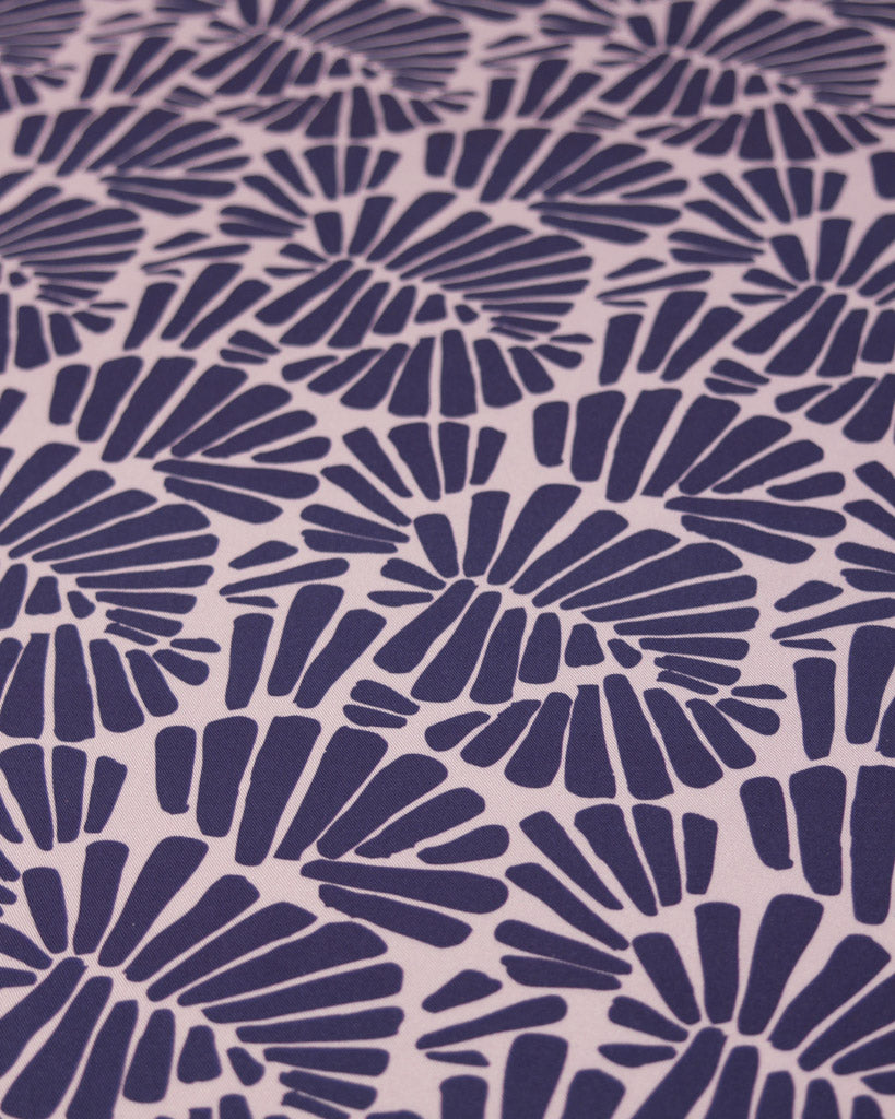 Viscose twill fabric featuring an all-over palm fan motif in deep, rich purple on a soft dusty mauve ground