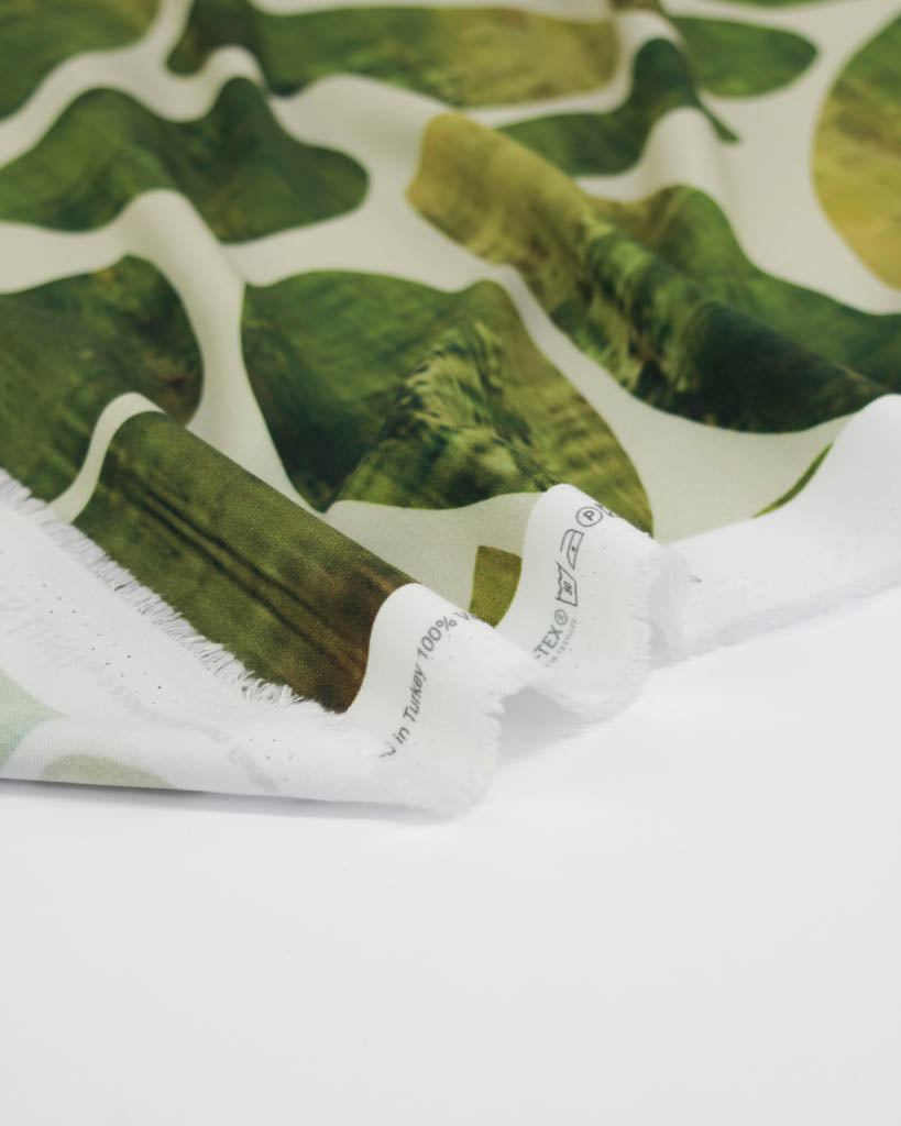 Green oval pattern viscose fabric on a white background with a brand label.
