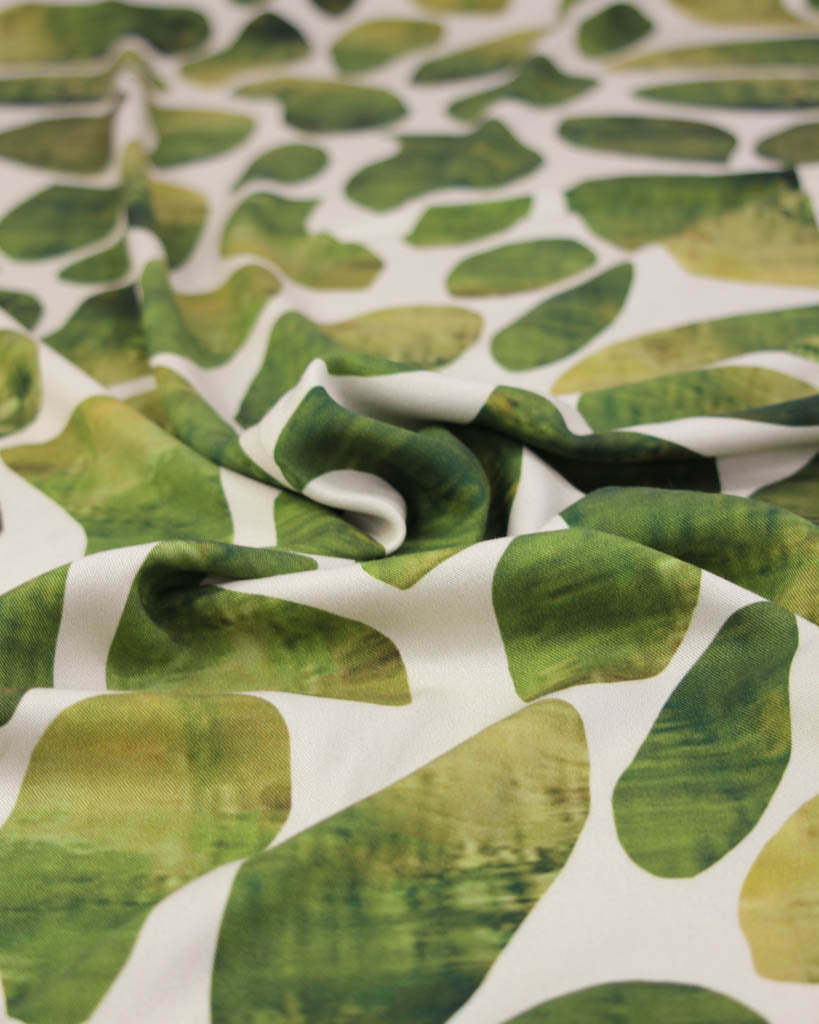 Close-up of green leaf pattern viscose twill fabric on a white background