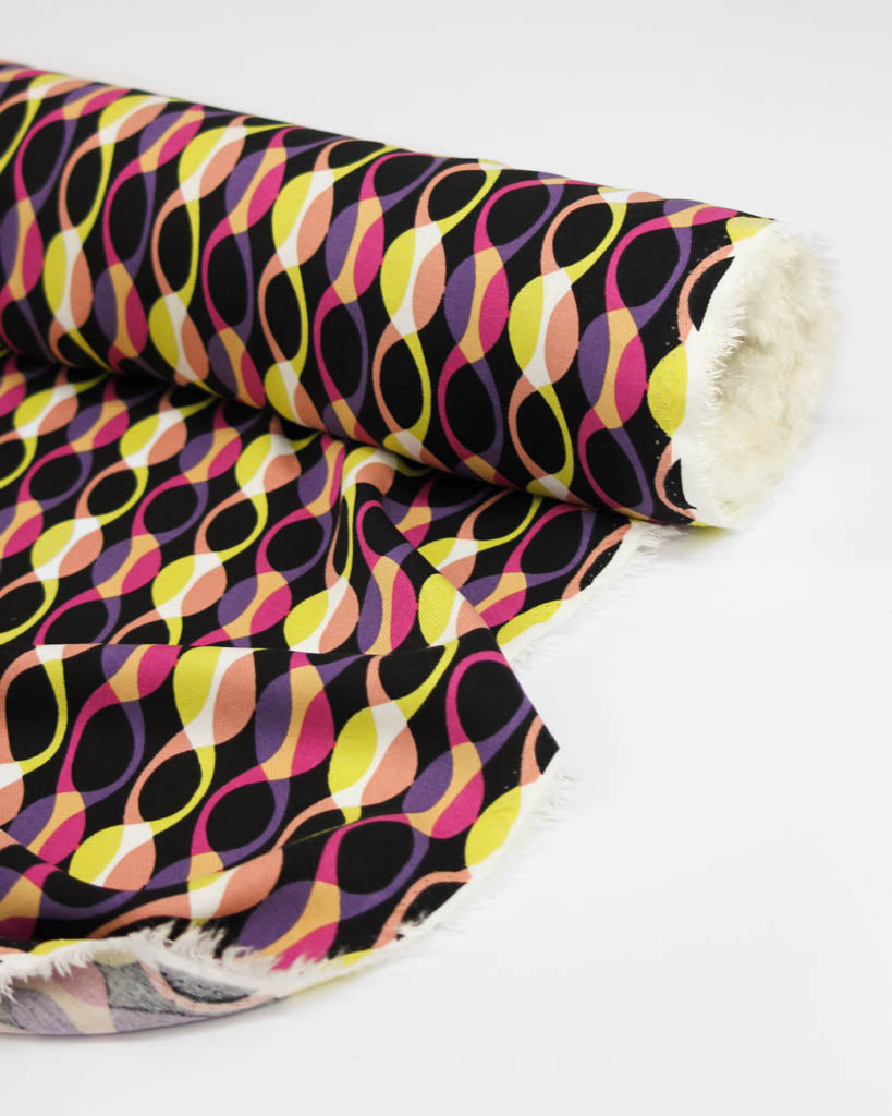 Colourful abstract patterned viscose twill fabric in pink, yellow and purple on a black background