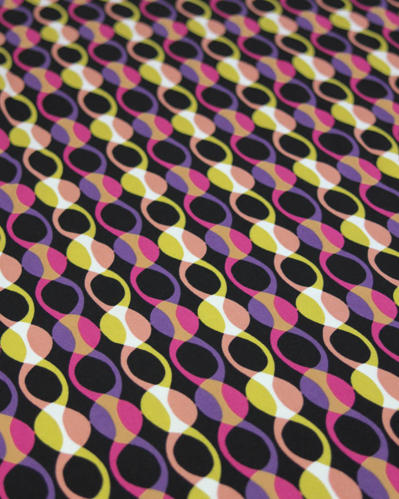 Colourful abstract patterned viscose twill fabric in pink, yellow and purple on a black background