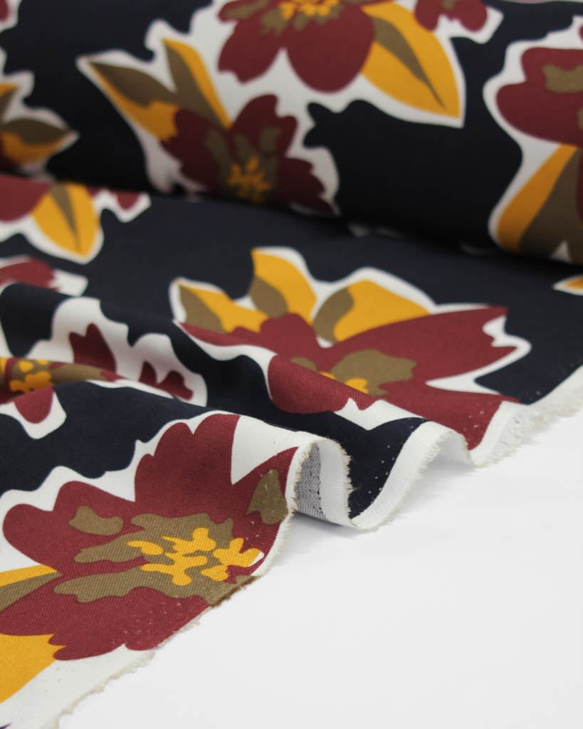 Floral viscose fabric with red, yellow, and green flowers on a black background