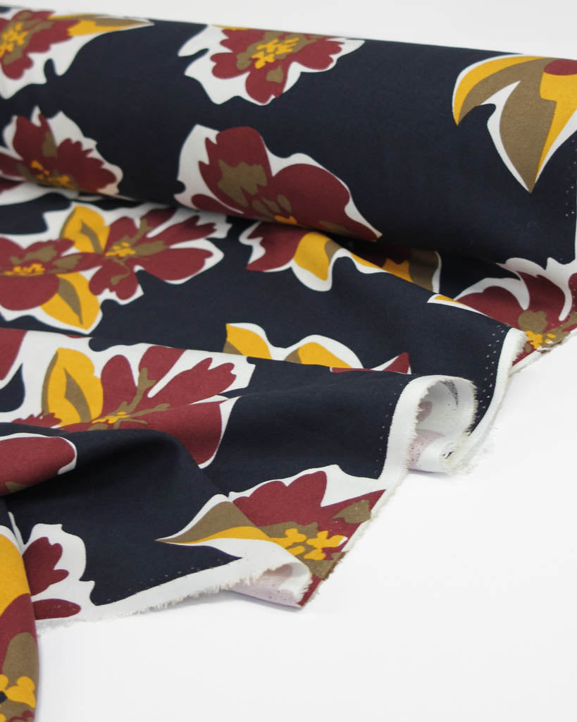 Floral patterned viscose fabric with red, yellow, and white colors on a dark blue background.