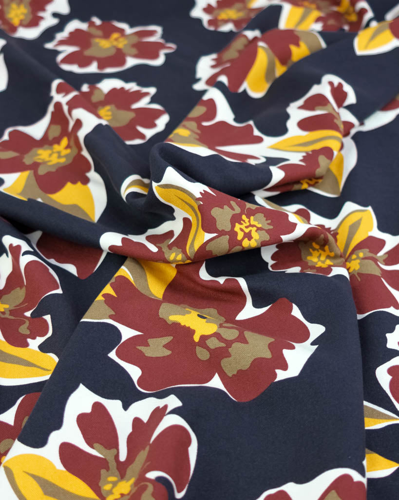 Floral patterned viscose twill fabric with red, yellow, and white flowers on a navy background