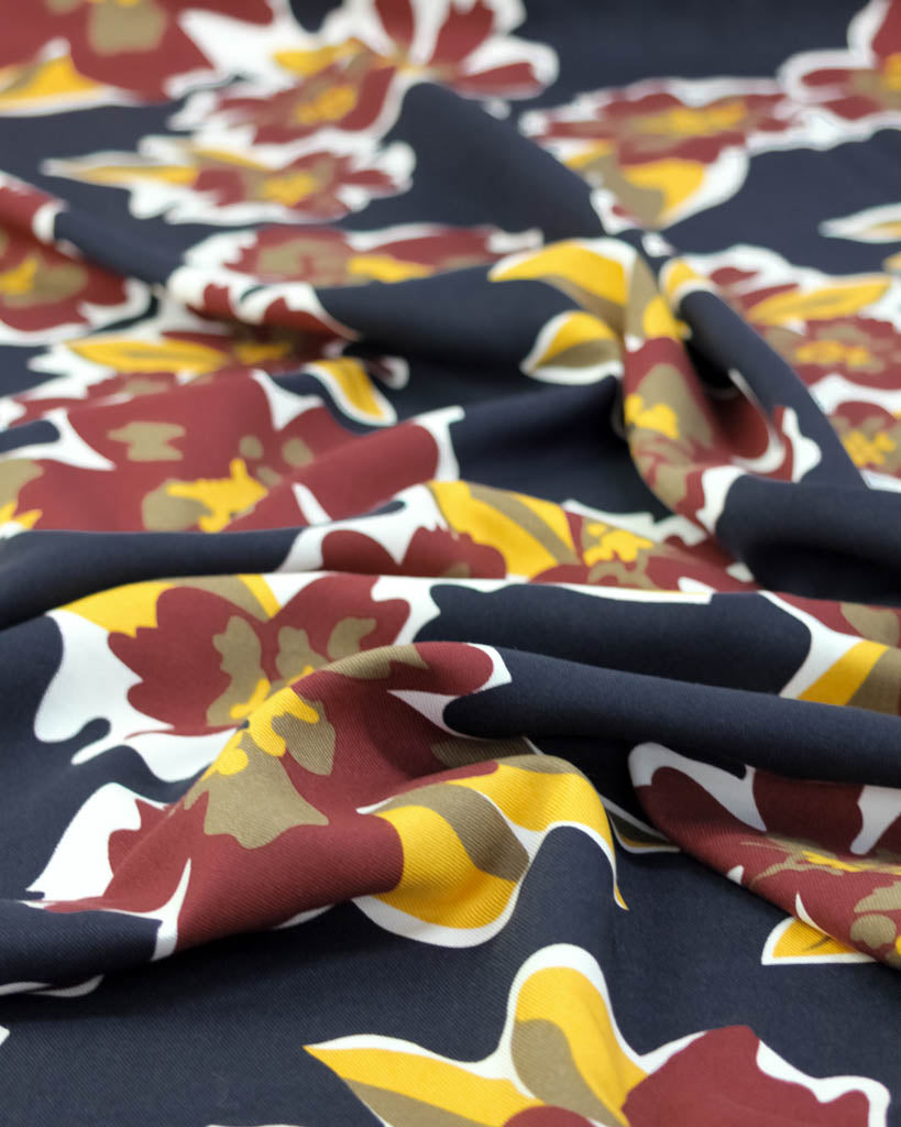 Close-up of floral patterned viscose fabric with navy, red, yellow, and white colors.