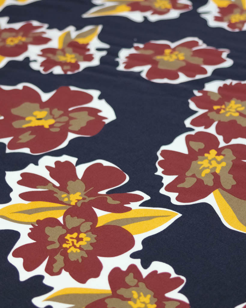 Close-up of floral pattern viscose fabric with red and yellow flowers on a navy background