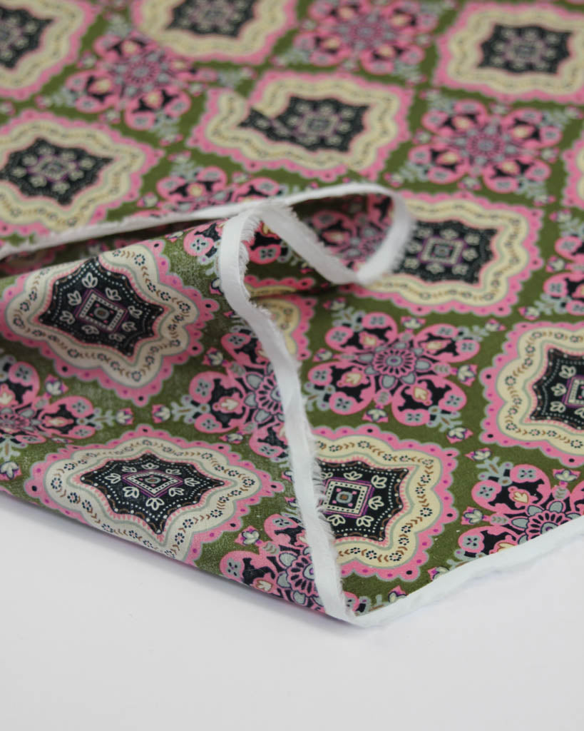 Patterned cotton lawn fabric with pink and green tile design on a white background