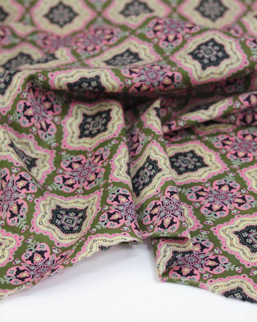 Patterned cotton lawn fabric with green, pink, and black tile design on a white background