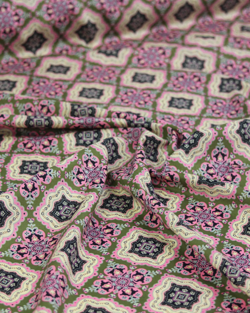 Close-up of patterned cotton lawn fabric with geometric design on a green background