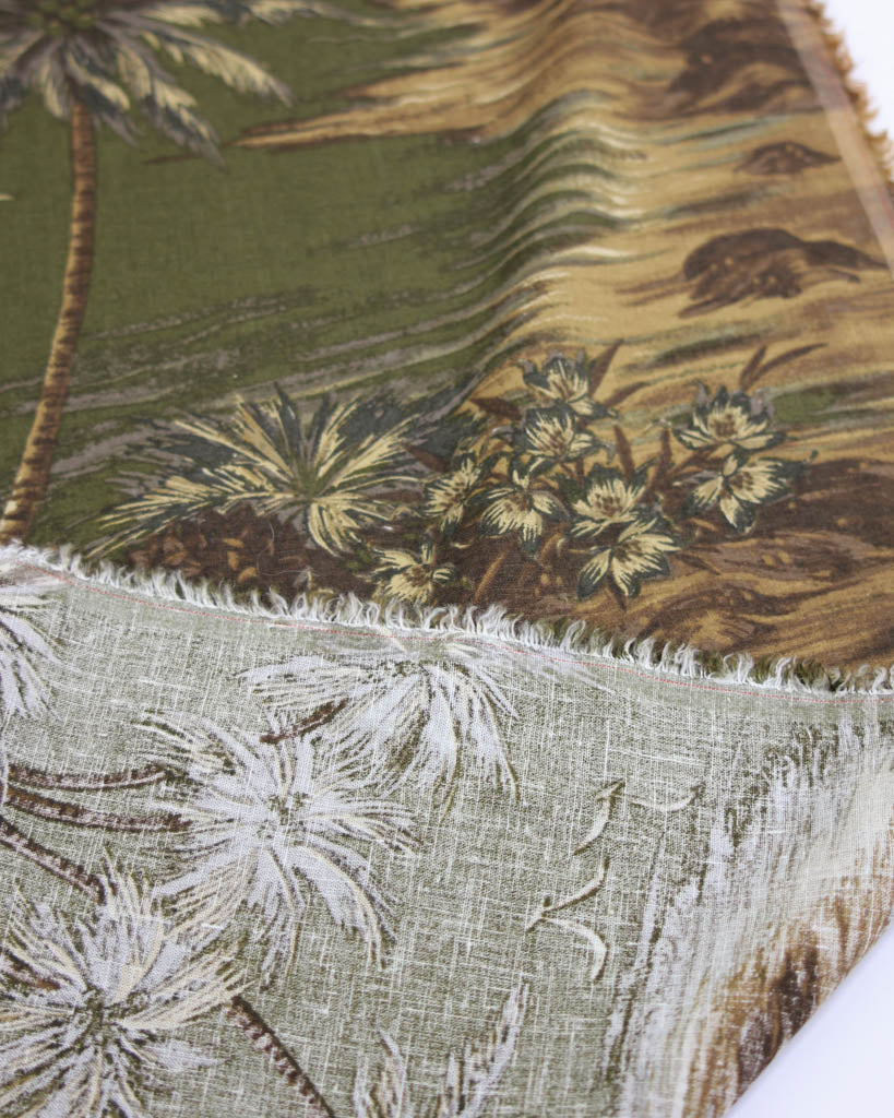 Close-up of a fabric with tropical pattern featuring palm trees and plants.