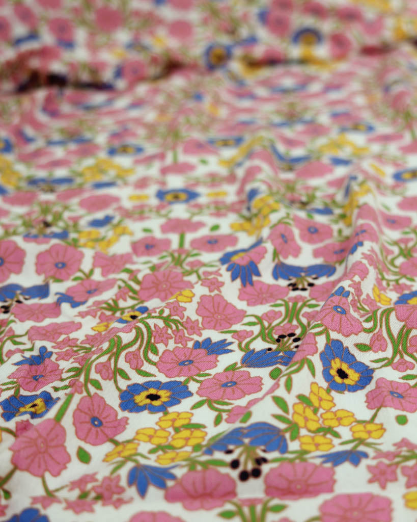 Close-up of colourful floral viscose fabric with pink, blue, yellow, and green flowers.