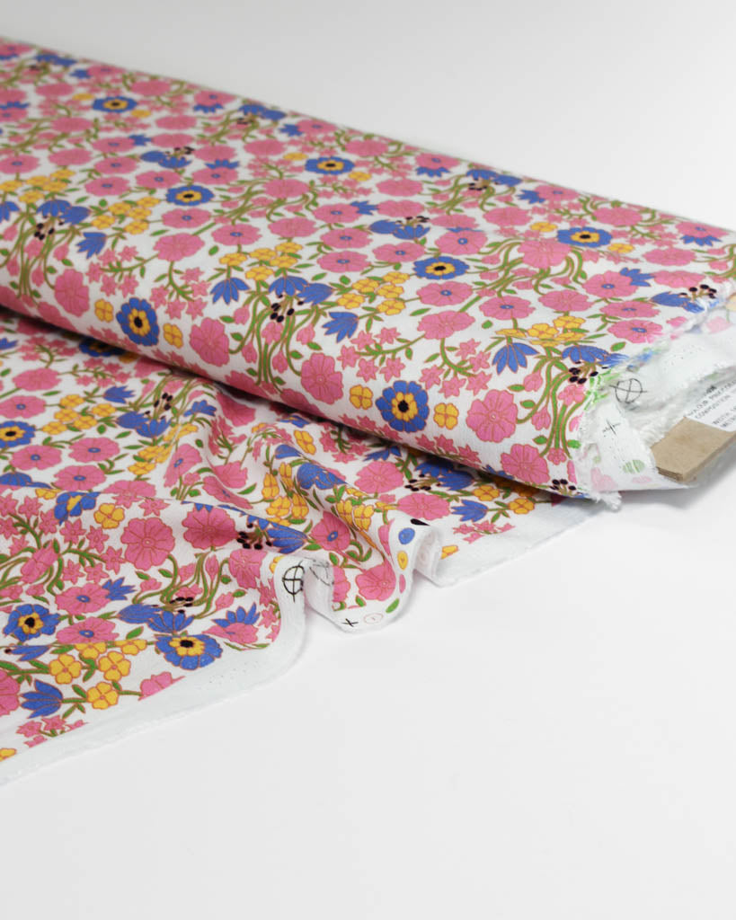 Floral viscose crepe fabric with pink, blue, and yellow flowers on a white background