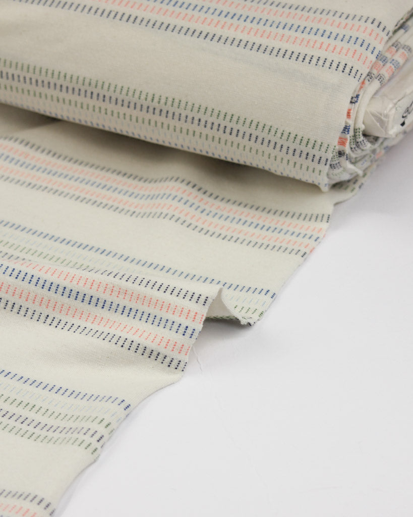 Close-up of striped cotton jersey fabric with a neutral color palette on a white background