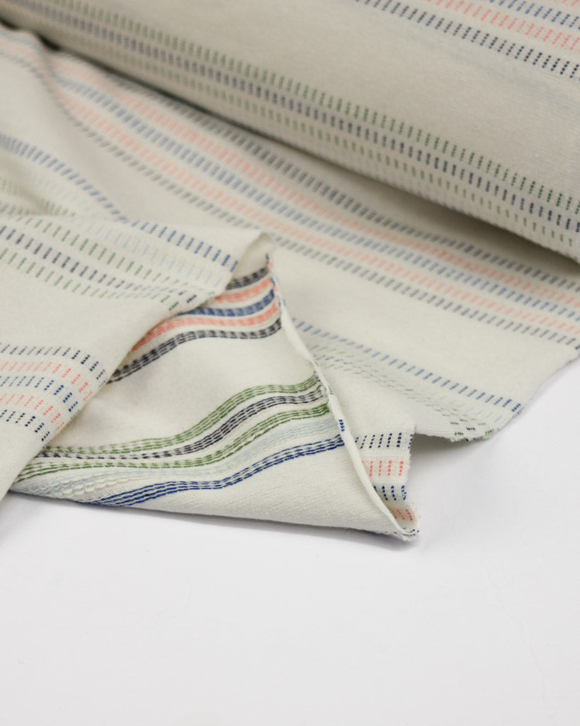 Folded cotton jersey fabric with multicolored stripes on a white background