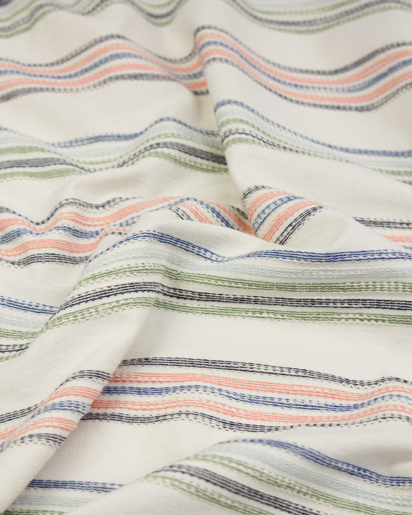 Close-up of striped cotton jersey fabric with multicolor pattern on a white background