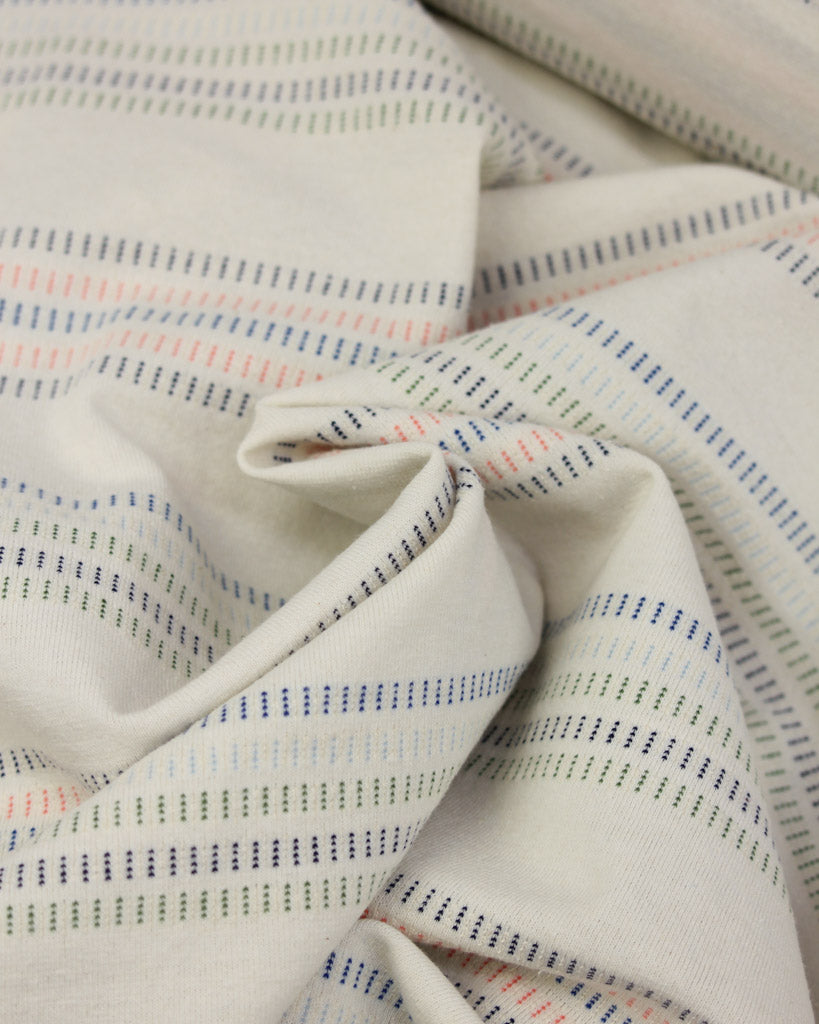 Close-up of cotton jersey fabric with multicolored stripes on a neutral background