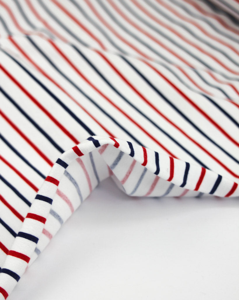 Close-up of striped cotton jersey fabric with red, white, and blue lines on a white background