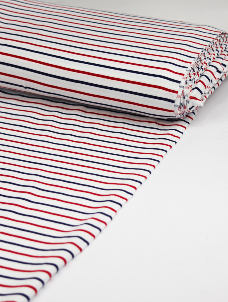 Striped cotton jersey fabric with red and blue lines on a white background