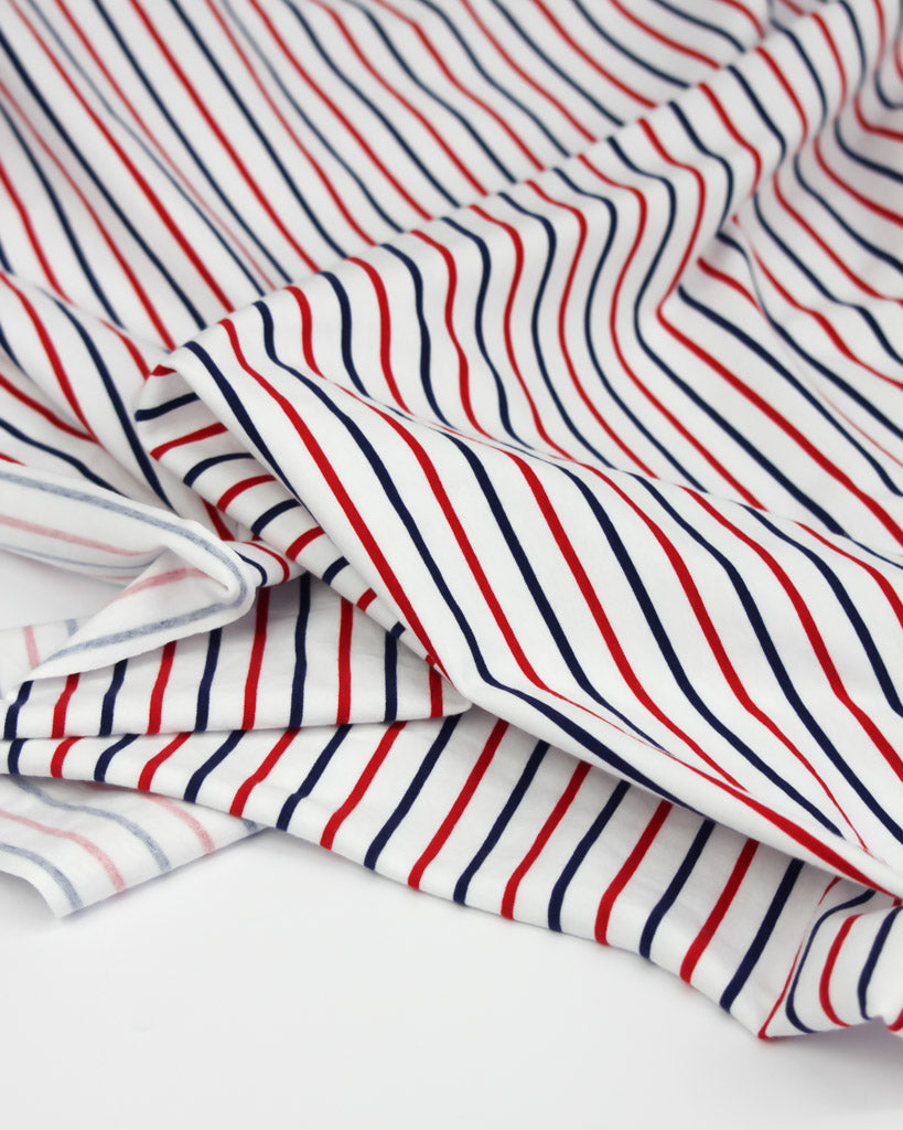 Striped cotton jersey fabric with red and blue lines on a white background