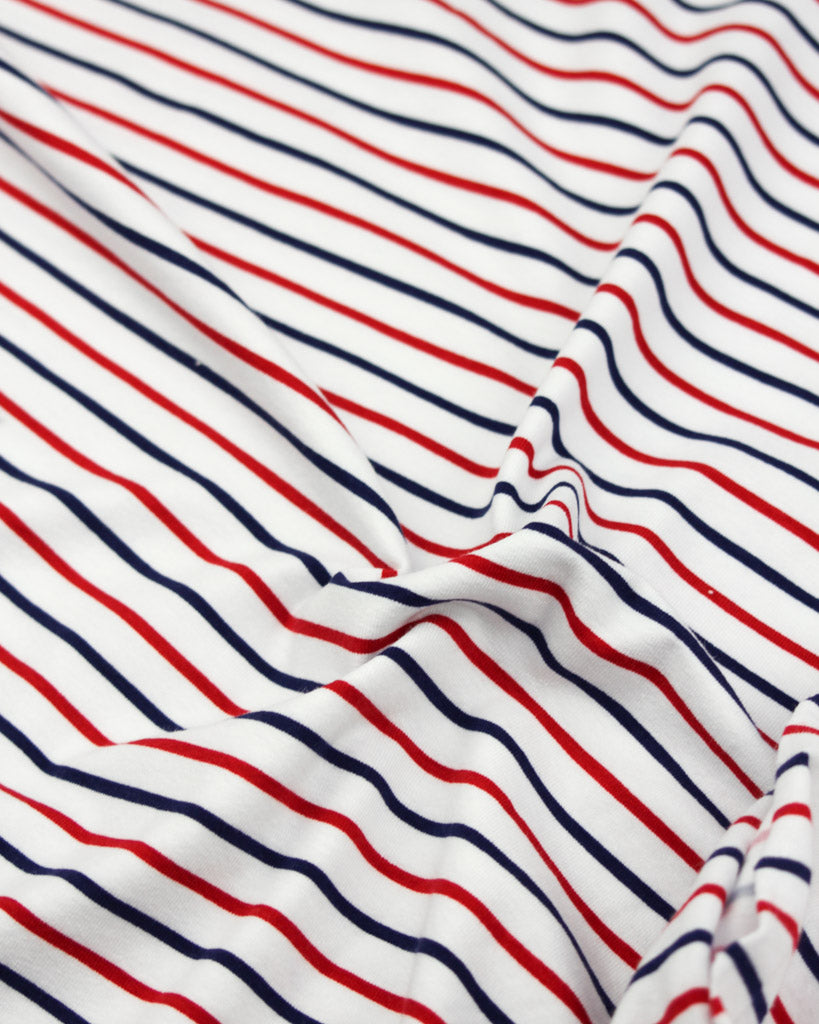 Striped cotton jersey fabric with red and blue lines on a white background