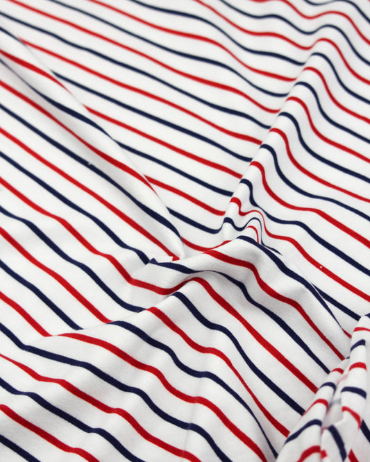 Striped cotton jersey fabric with red and blue lines on a white background