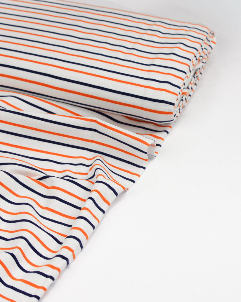 Striped cotton jersey fabric with orange and navy lines on a white background