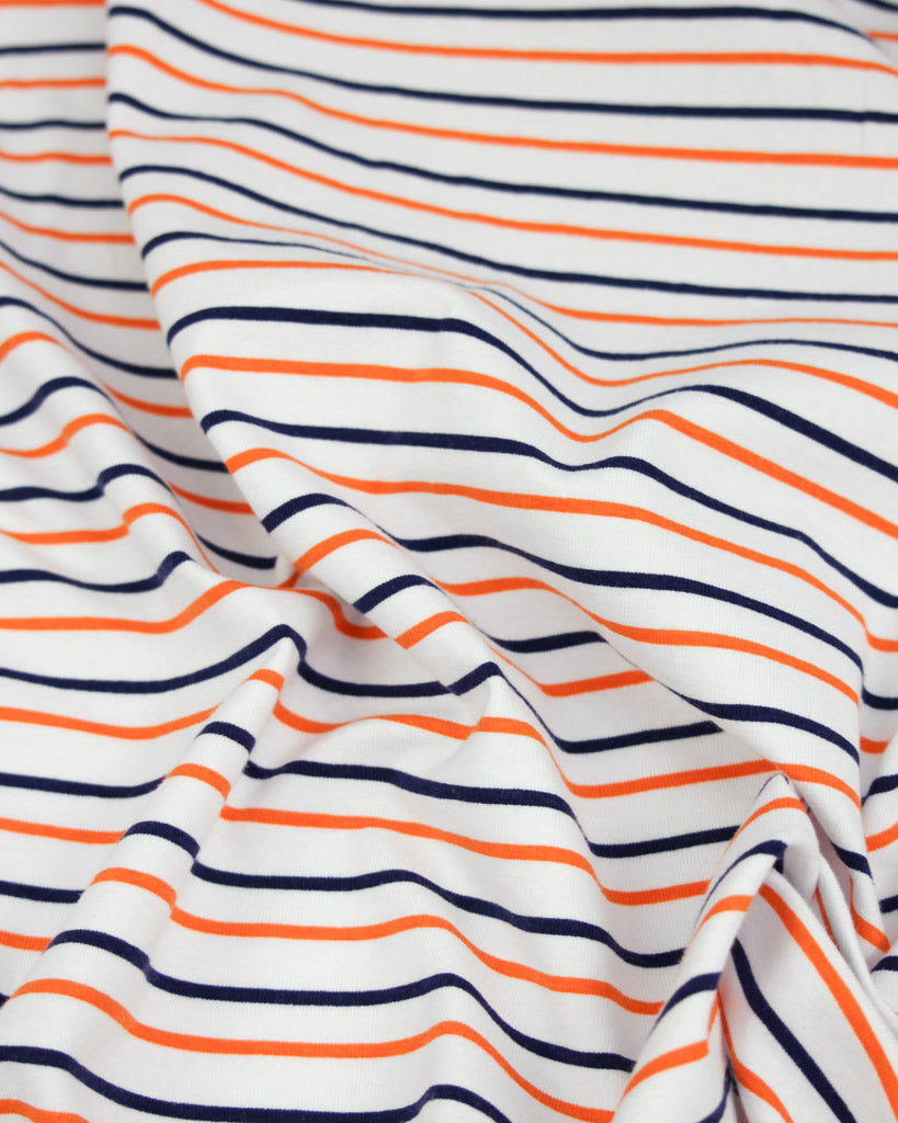 Close-up of striped cotton jersey fabric with orange and navy lines on a white background