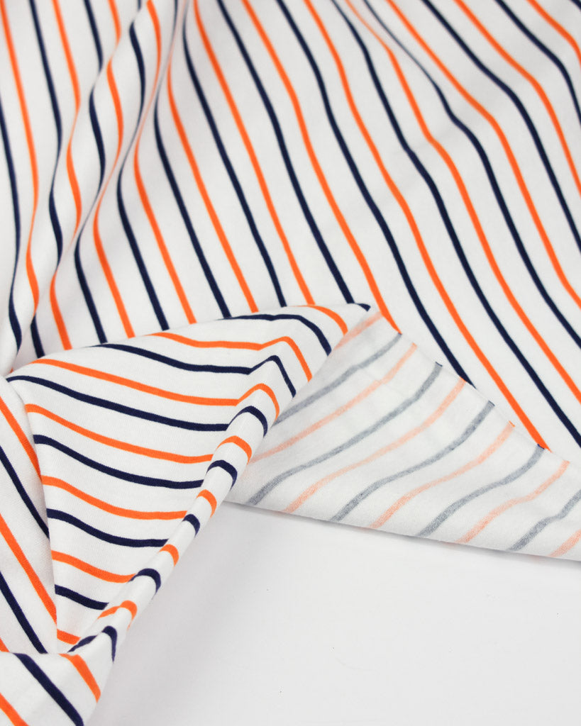 Striped cotton jersey fabric with orange and navy lines on a white background
