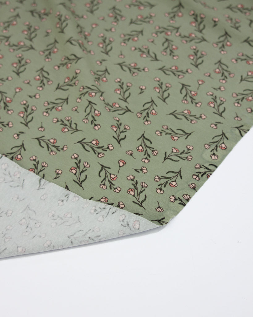 Green stretch cotton jersey fabric with floral pattern on a white background