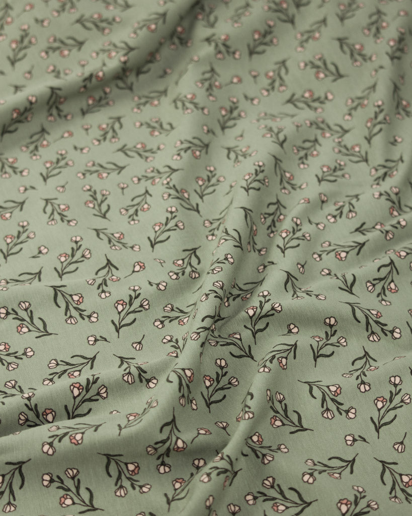 Stetch jersey fabric with small floral pattern on a green background