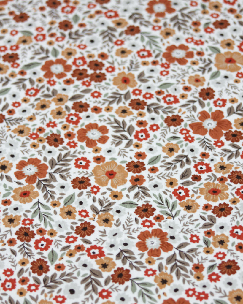 Patterned fabric with small flowers in orange, red, and brown on a white background