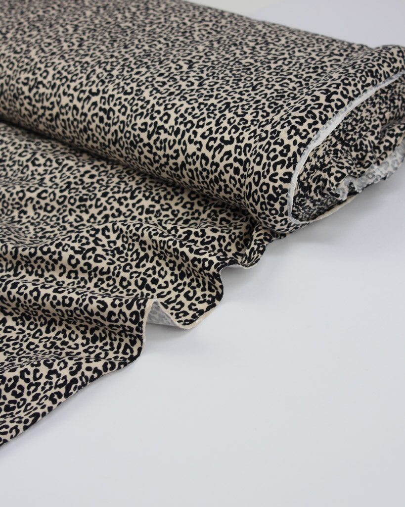Roll of leopard print cotton jersey fabric on a white background