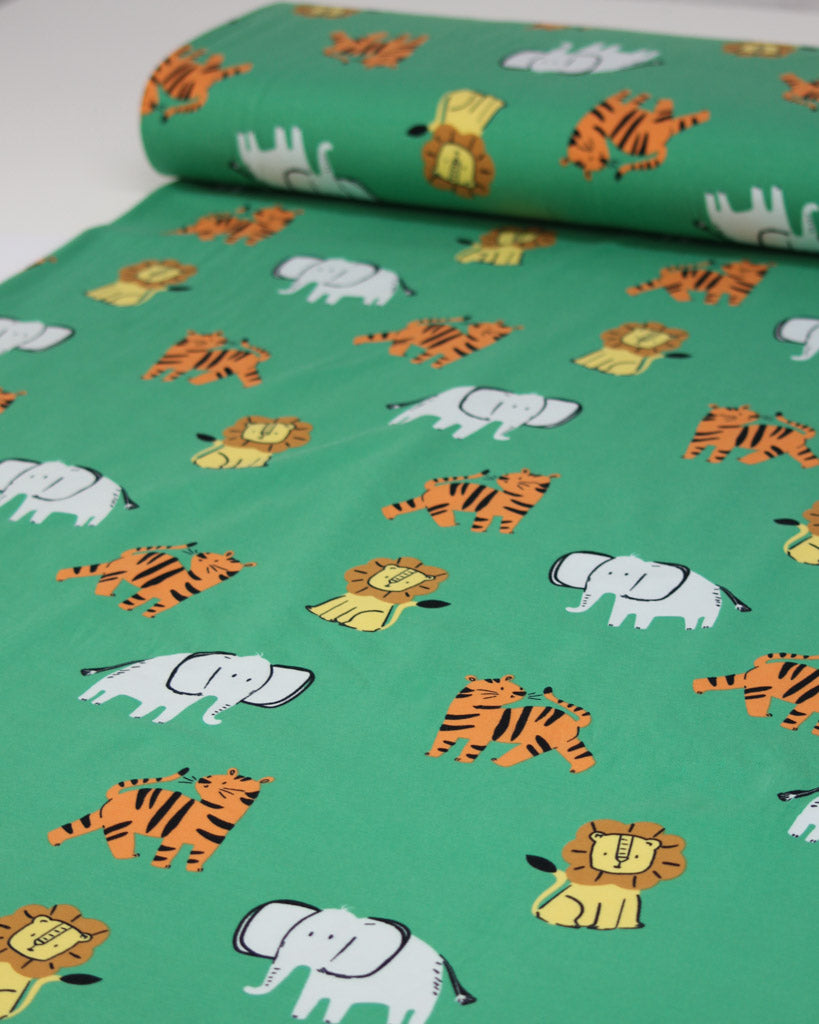 Cotton jersey fabric with animal pattern of lions, tigers and elephants on a green background
