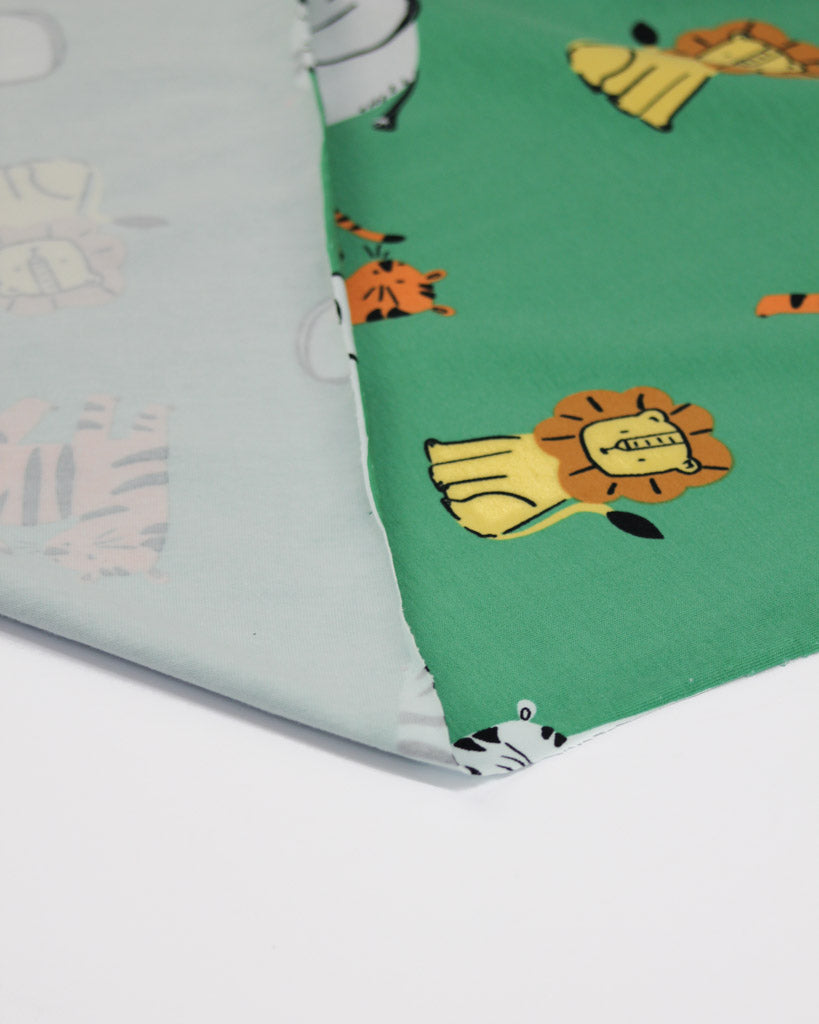 Cotton jersey fabric with lion and tiger pattern on a green background