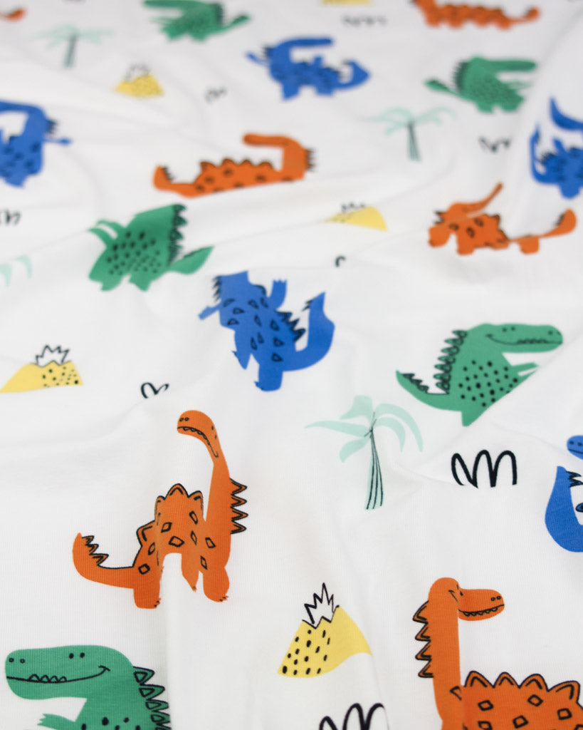Cotton jersey fabric with colourful dinosaur pattern on a white background