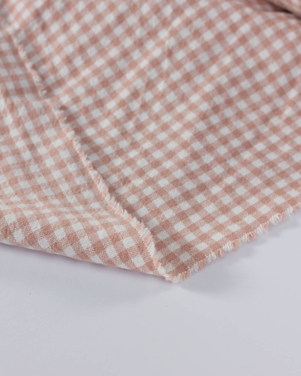 Close-up of pink and white checkered gingham cotton fabric on a white background