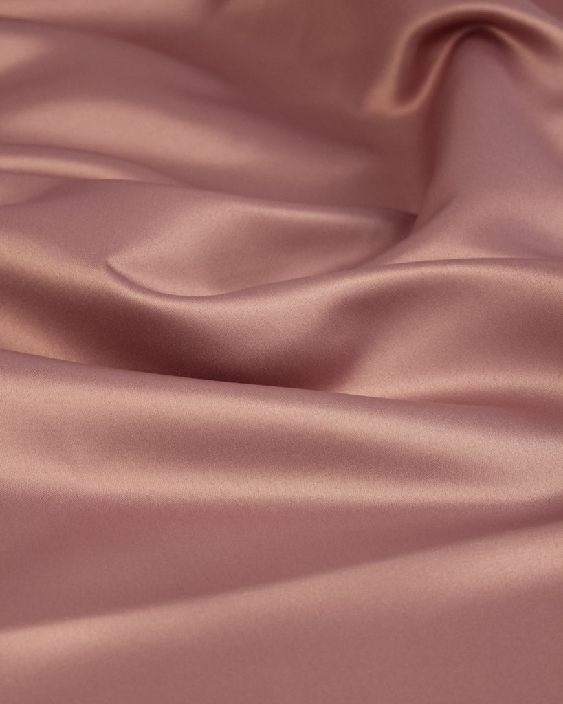 Close-up of smooth, pink satin fabric with folds