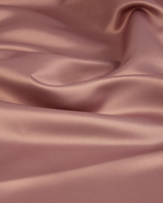 Close-up of smooth, pink satin fabric with folds
