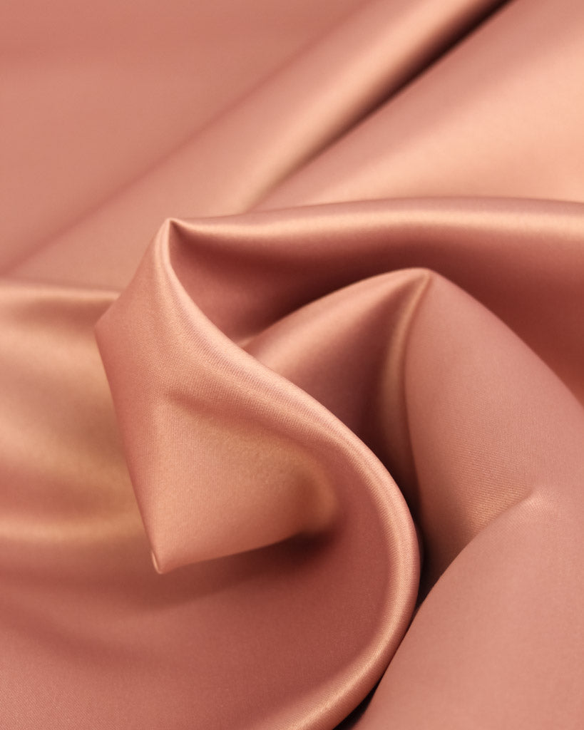 Close up of warm pink toned duchess satin fabric