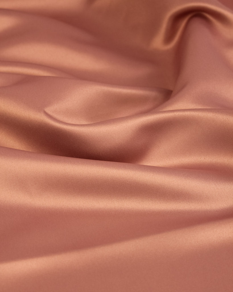 Close-up of smooth, pink satin fabric with folds