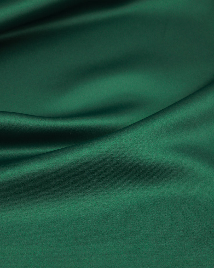 Close-up of dark green satin fabric with folds