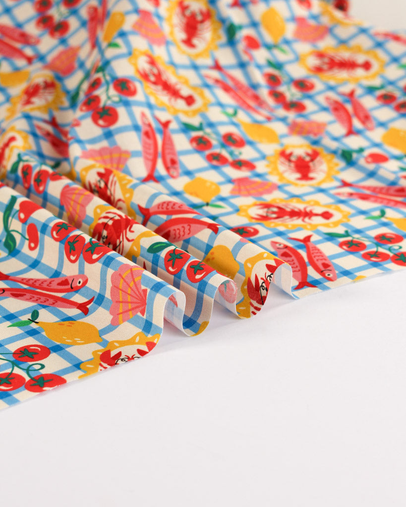 Colourful fabric with fish and shell pattern on a checkered white background