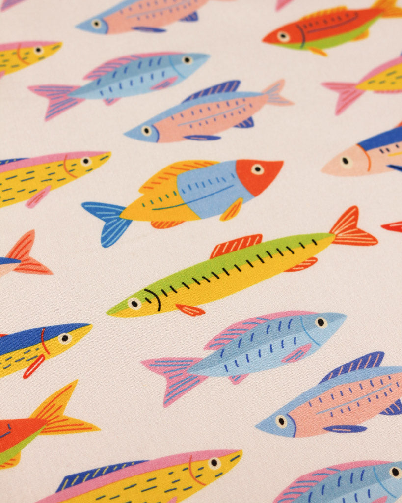 Cotton fabric with rainbow colourful fish repeat pattern on a white background