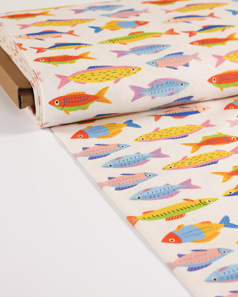 Roll of cotton fabric with colourful fish pattern on a white background