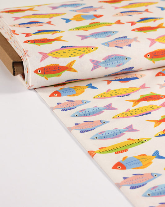 Roll of cotton fabric with colourful fish pattern on a white background